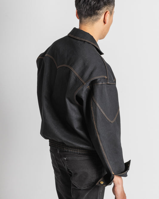 This color image shows a model wearing the black denim jacket Stratocruiser. The model is turned away from the camera showing the quarter rear part, where we can see the unique layering and stitching of the jacket.